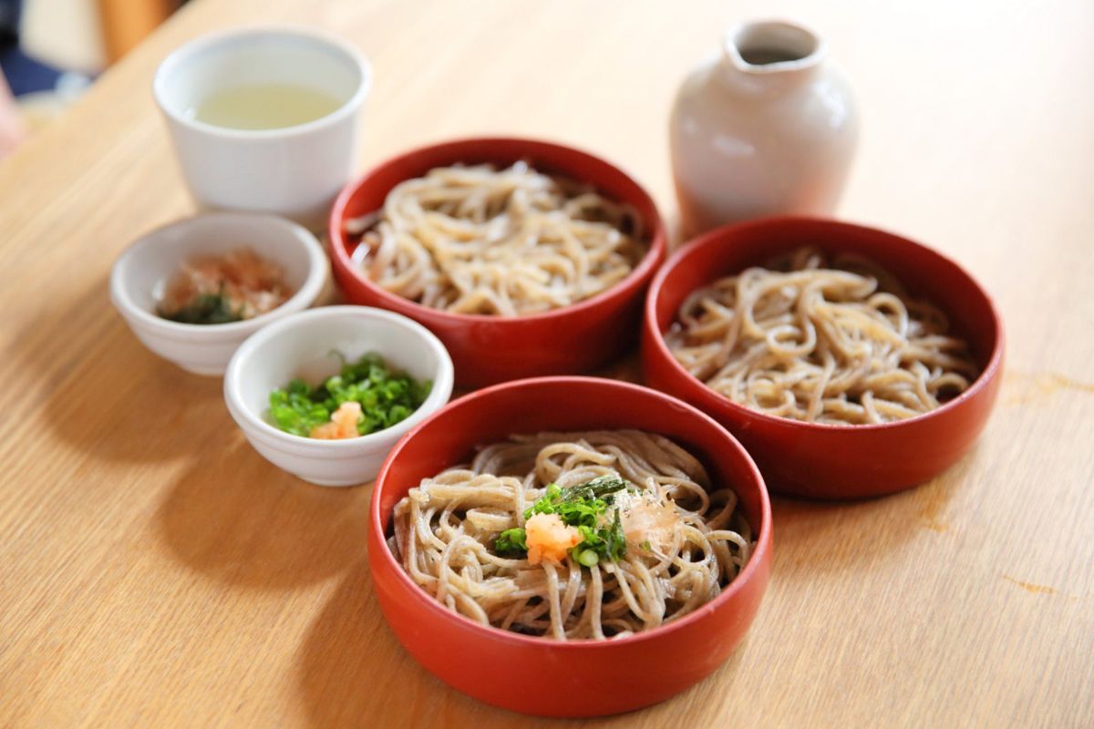 朱塗りの丸い器に盛った出雲の割子そばと、薬味、そば湯